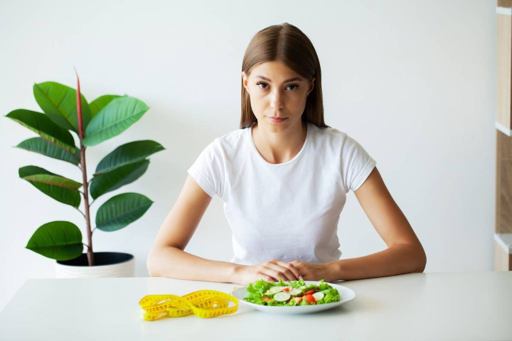 Young woman on a diet, eats only salad and tries to lose weight.