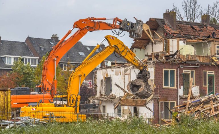 Two Demolition cranes demolishing old row of houses in the Netherlands